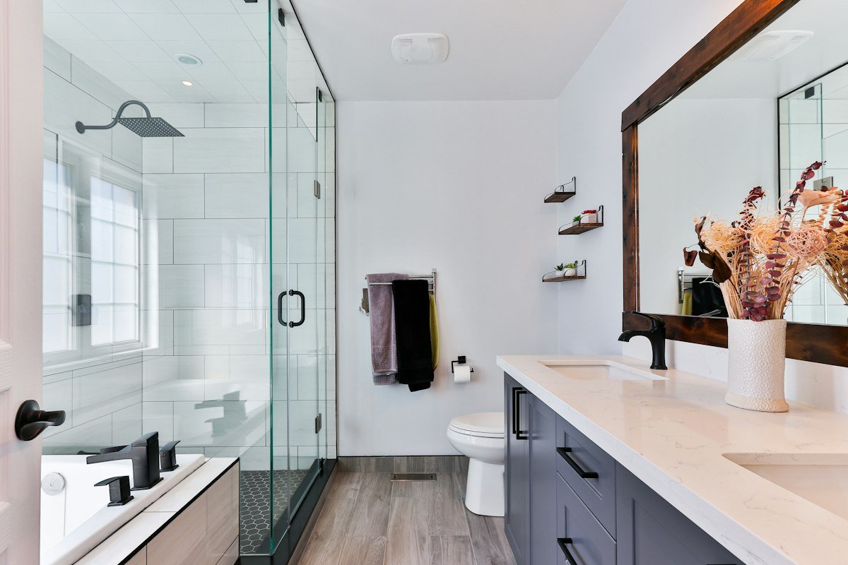 Before remodel: Dated enclosed shower stall with high curb and tile mold.