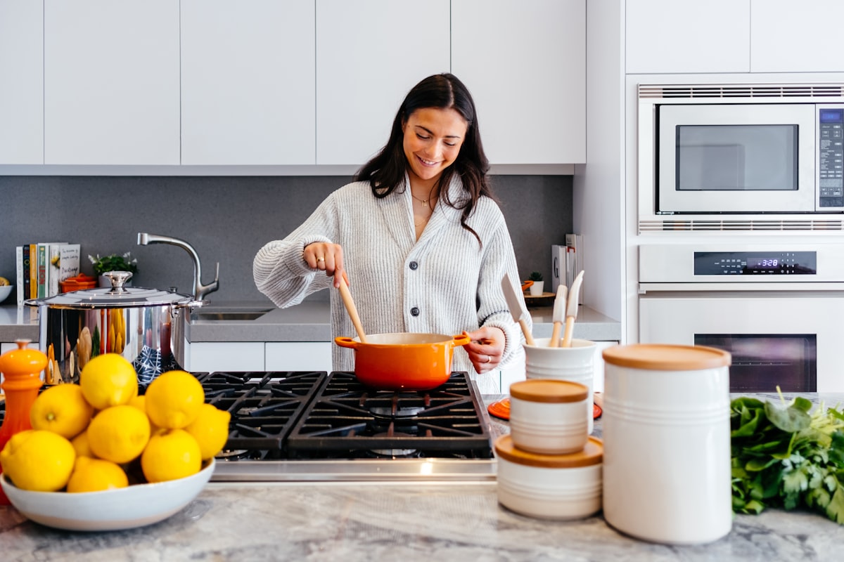 Homeowner cooking in a warm, welcoming kitchen with marble countertop, fresh ingredients, and natural sunlight.